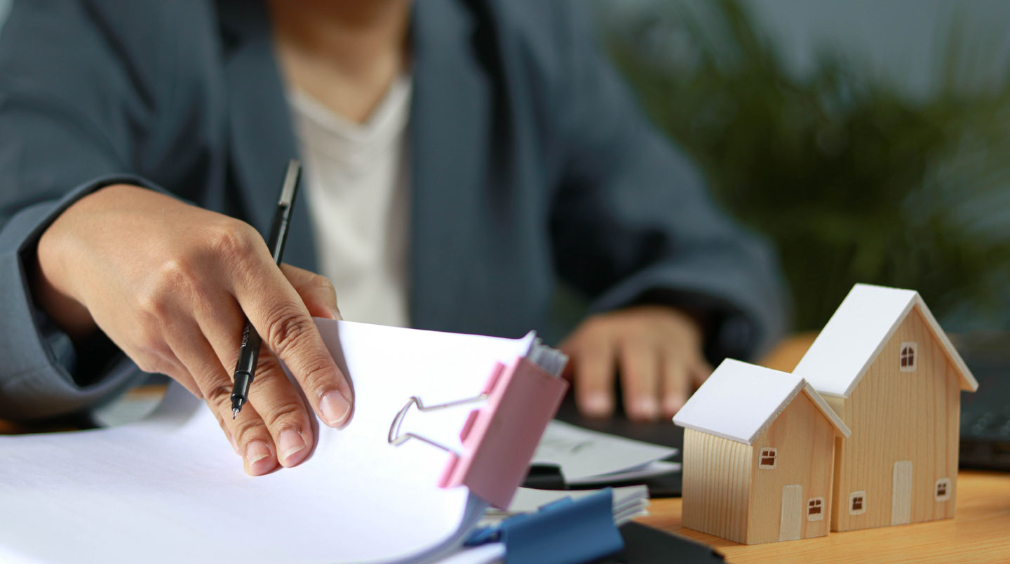 Vue aérienne d'un bureau avec pile organisée de documents administratifs français (bulletins de salaire, avis d'imposition, relevés bancaires) rangés dans un classeur, main triant les pièces